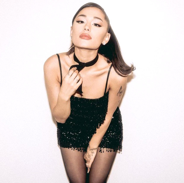 Ariana Grande stuns in a mini black dress with glitter details, stockings and signature high pony tail