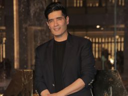 Manish Malhotra poses for paps dressed in a black suit